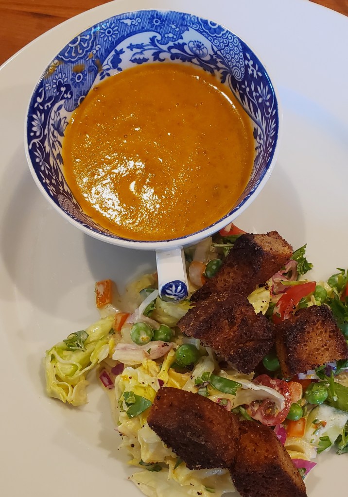 a cup of tomato soup and a salad